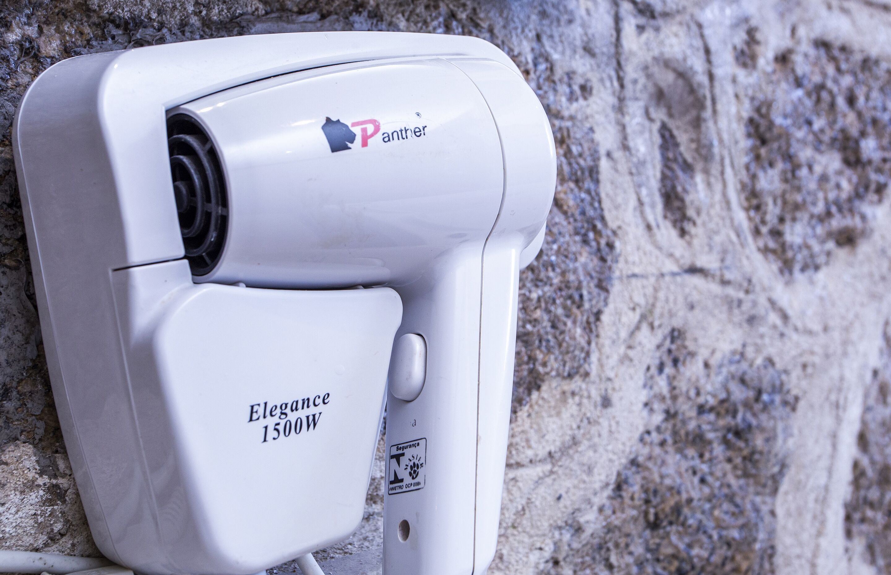 Una cámara de seguridad blanca con la marca 'Panther' y modelo 'Elegance 1500W' montada en una pared con textura.
