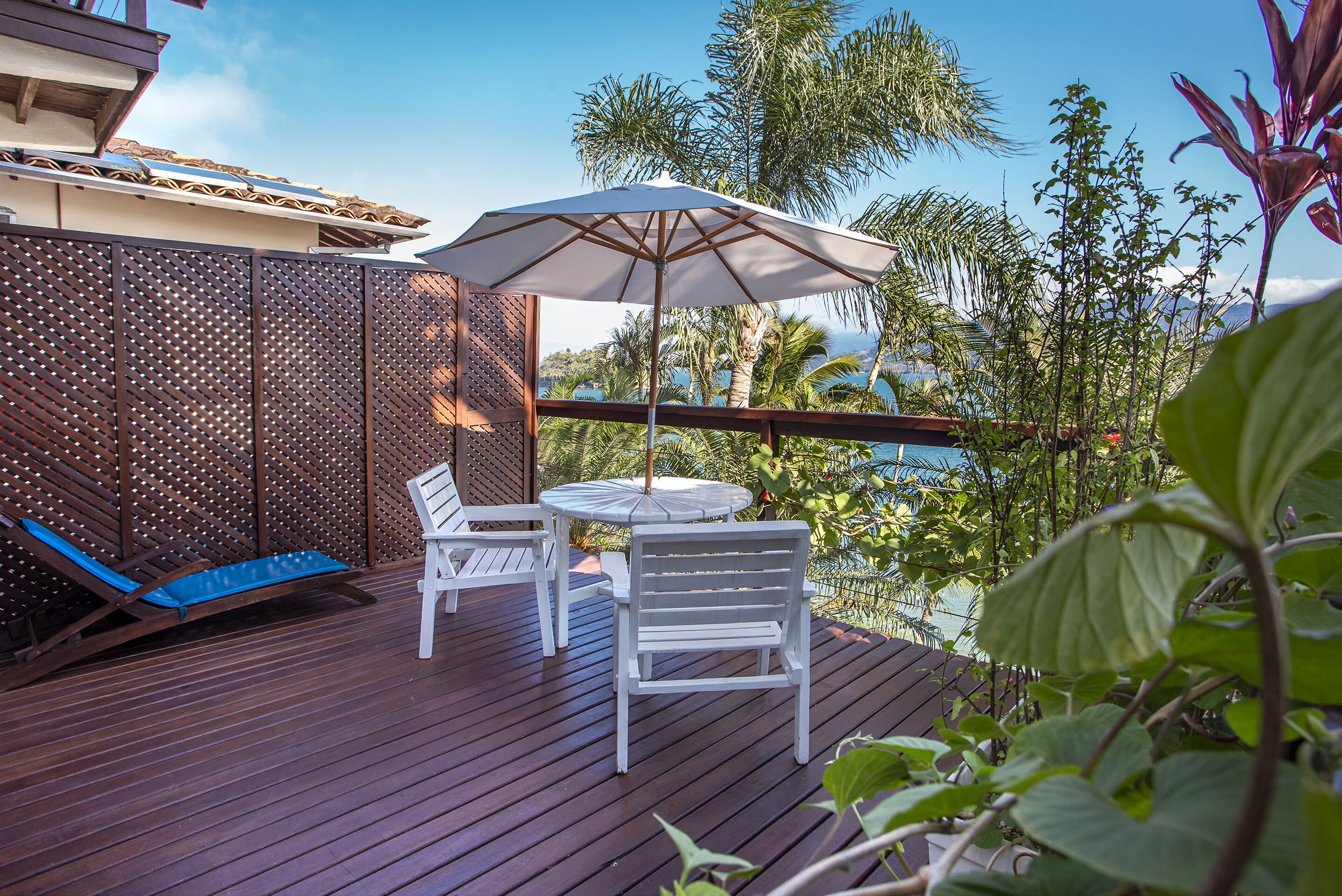 A wooden deck with a table and chairs, a blue lounge chair, and an umbrella.
