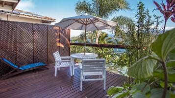 A wooden deck with a table and chairs, a blue lounge chair, and an umbrella.
