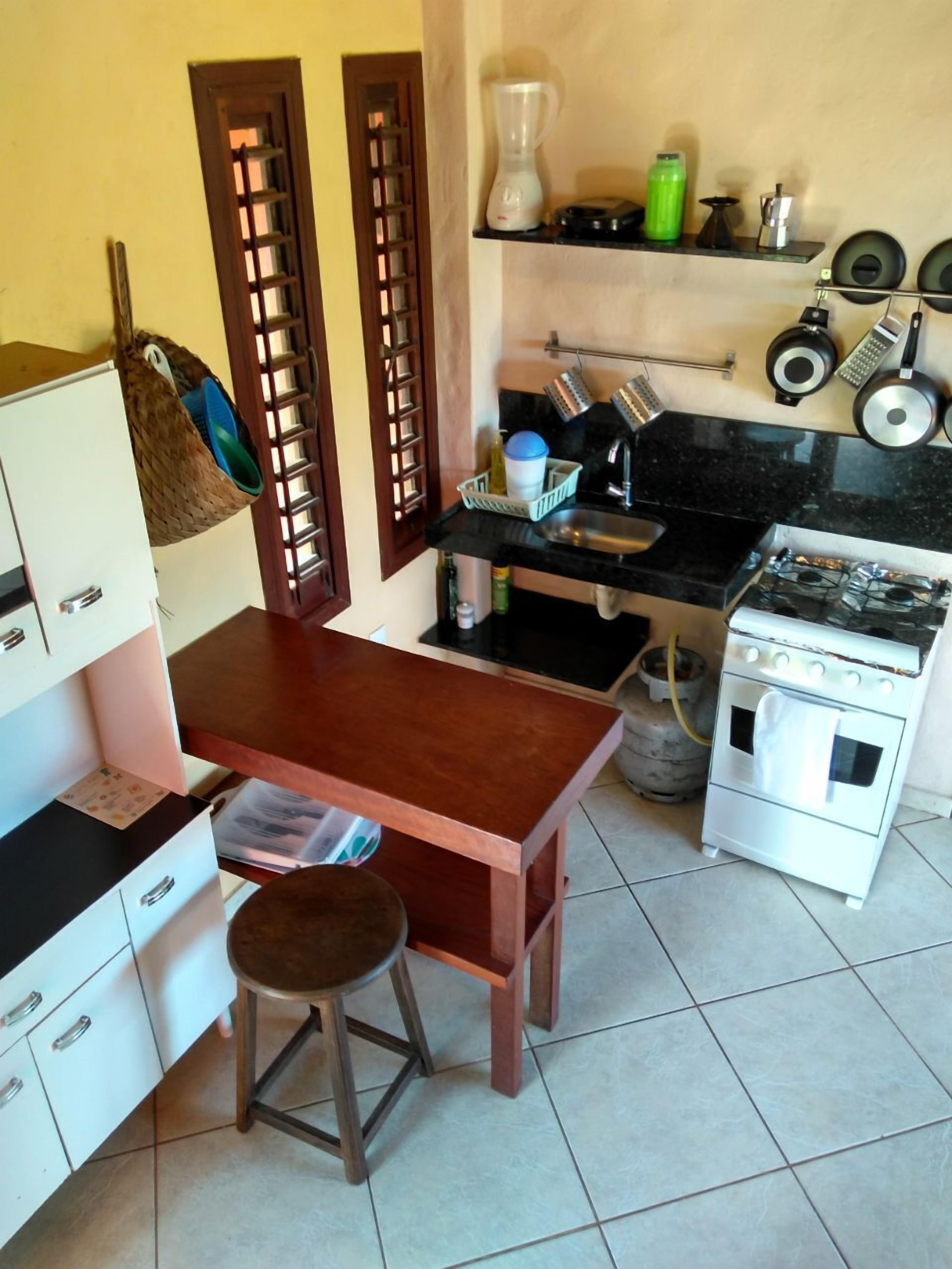 Een kleine keuken met een houten tafel, een gasfornuis en een gootsteen.