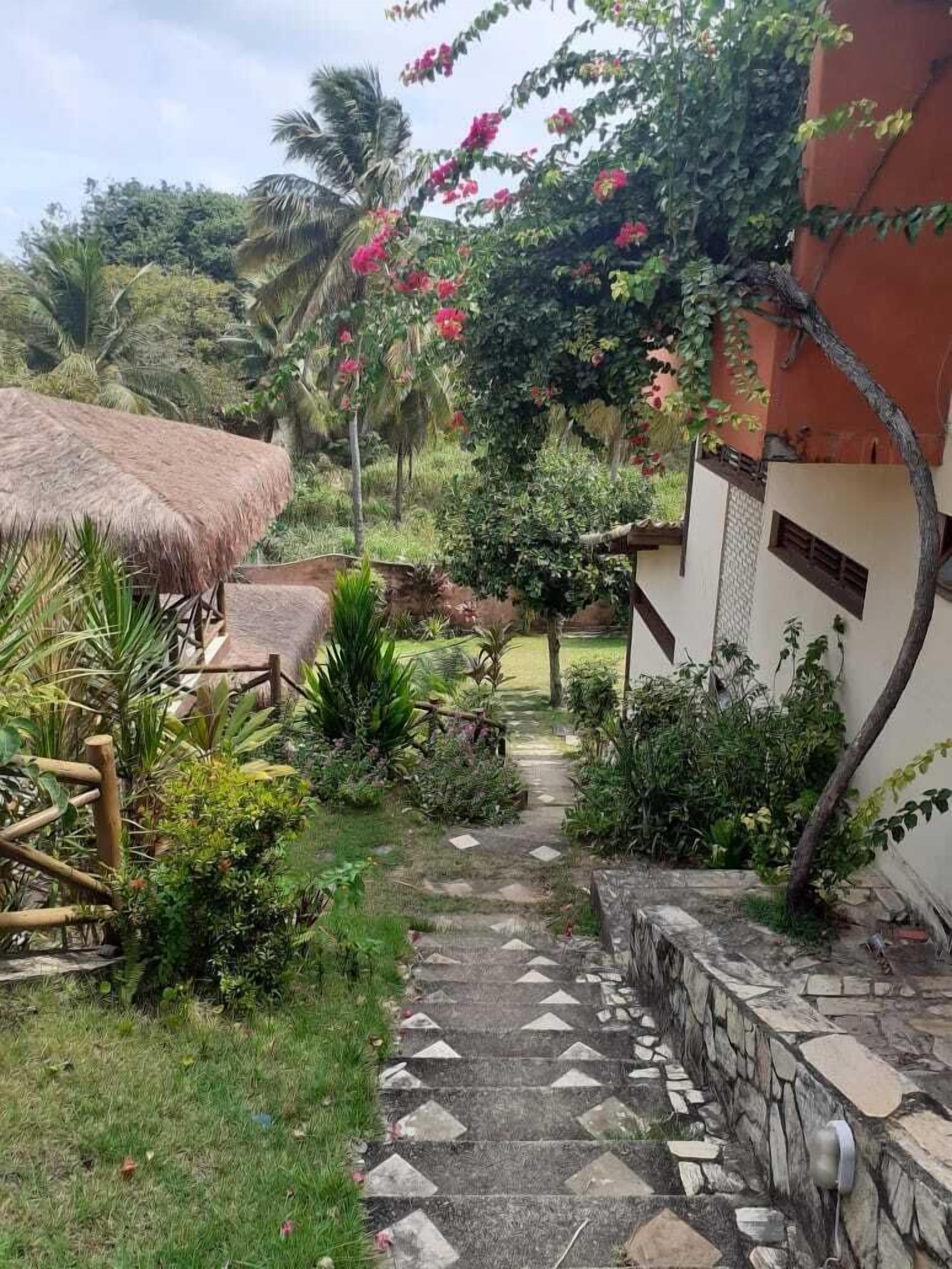 Un sendero en un jardín que lleva a un edificio con techo de paja y paredes de piedra.