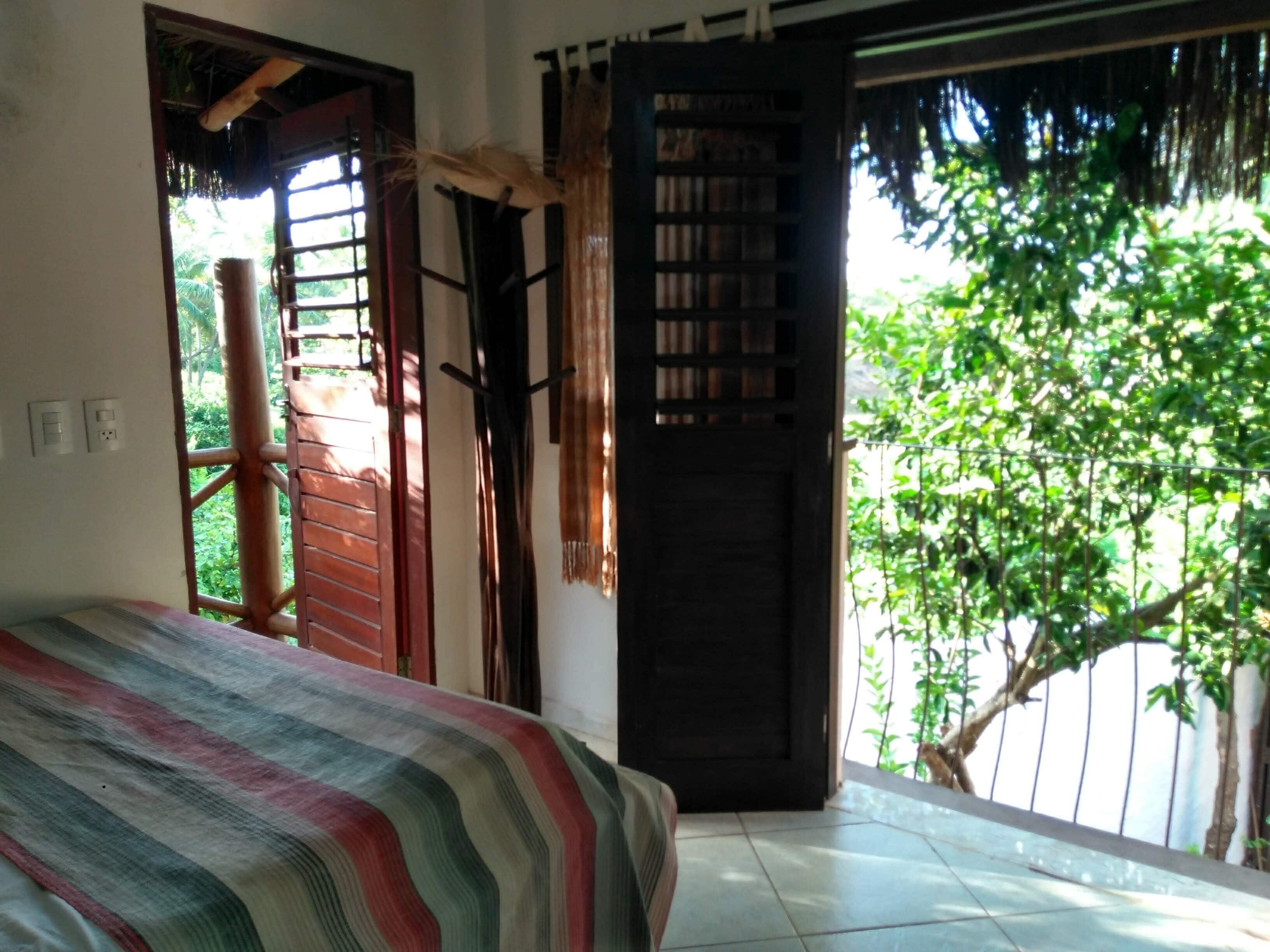 Ein Schlafzimmer mit einem Bett, einer Holztür und Blick auf Grünfläche draußen.