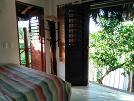 Un dormitorio con cama, una puerta de madera y vista a zonas verdes.