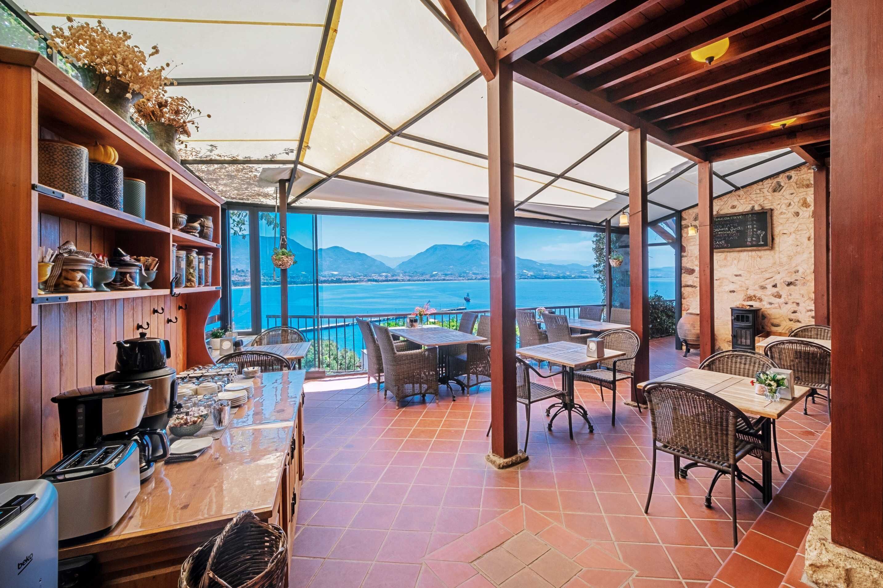 A covered outdoor dining area with a view of the sea and mountains.