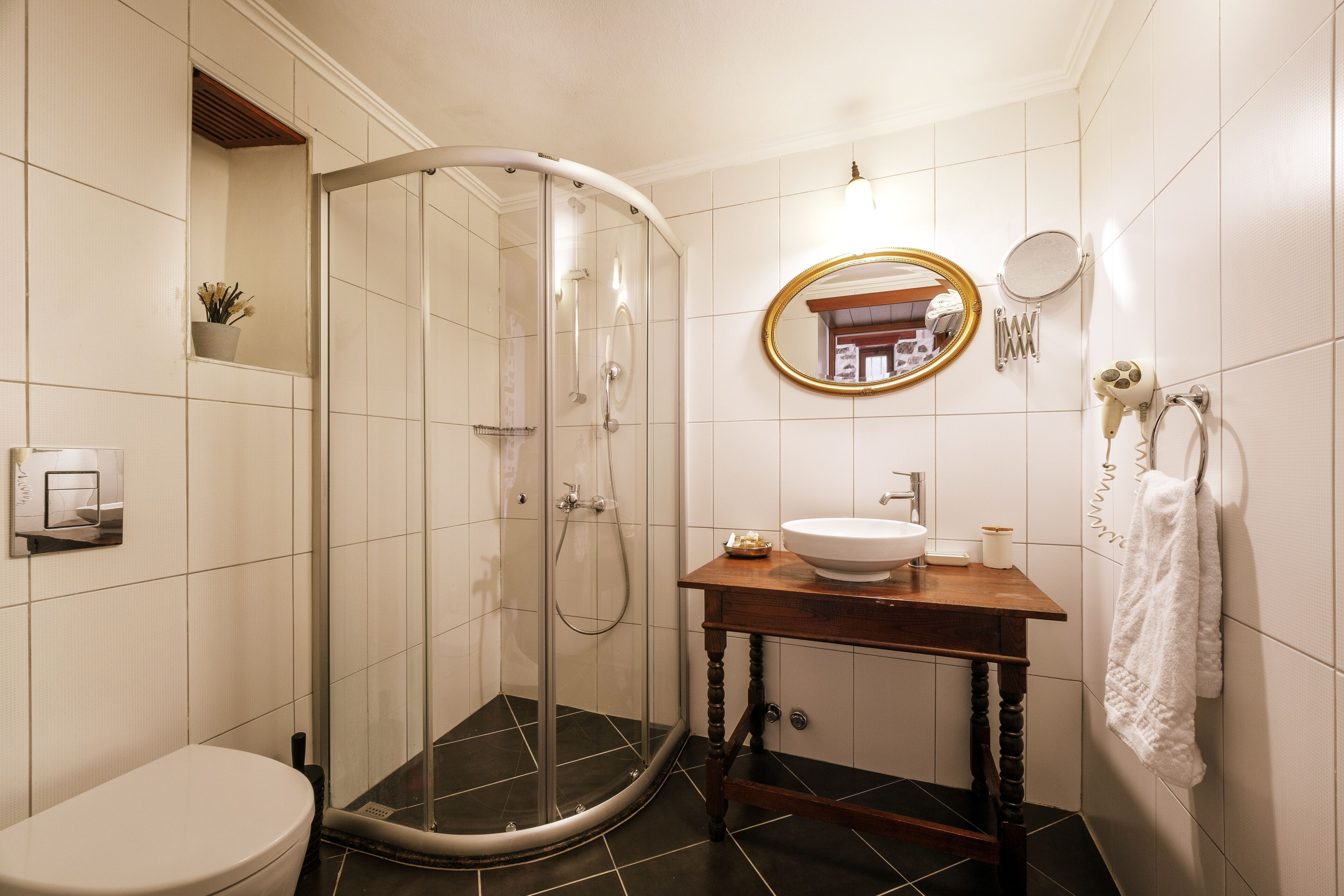 A bathroom with a glass-enclosed shower, a toilet, a sink with a mirror, and a towel rack.