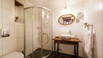 A bathroom with a glass-enclosed shower, a toilet, a sink with a mirror, and a towel rack.