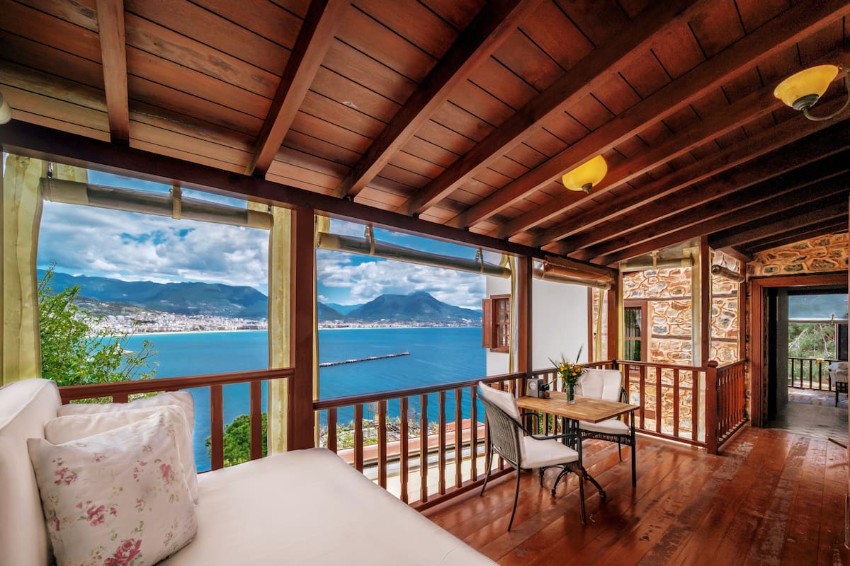 A wooden balcony with a view of a body of water and mountains.
