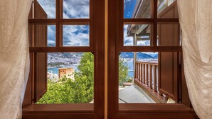 A view from a window with multiple panes, overlooking a coastal area with a castle, greenery, and a clear sky. - Hotel Villa Turka (Alanya)