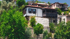 A hillside property with multiple buildings, including a two-story house with a balcony and a stone wall. - Hotel Villa Turka (Alanya)
