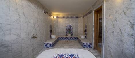 A bathroom with marble walls, a patterned floor, and two sinks with decorative tiles.
