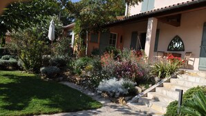 Una casa con una escalera de piedra que da a un porche, rodeada de plantas y arbustos.
