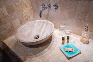 A bathroom with a large, round stone sink, two faucets, and a blue soap dish. - La Bégude du Pascouren (Fayence)