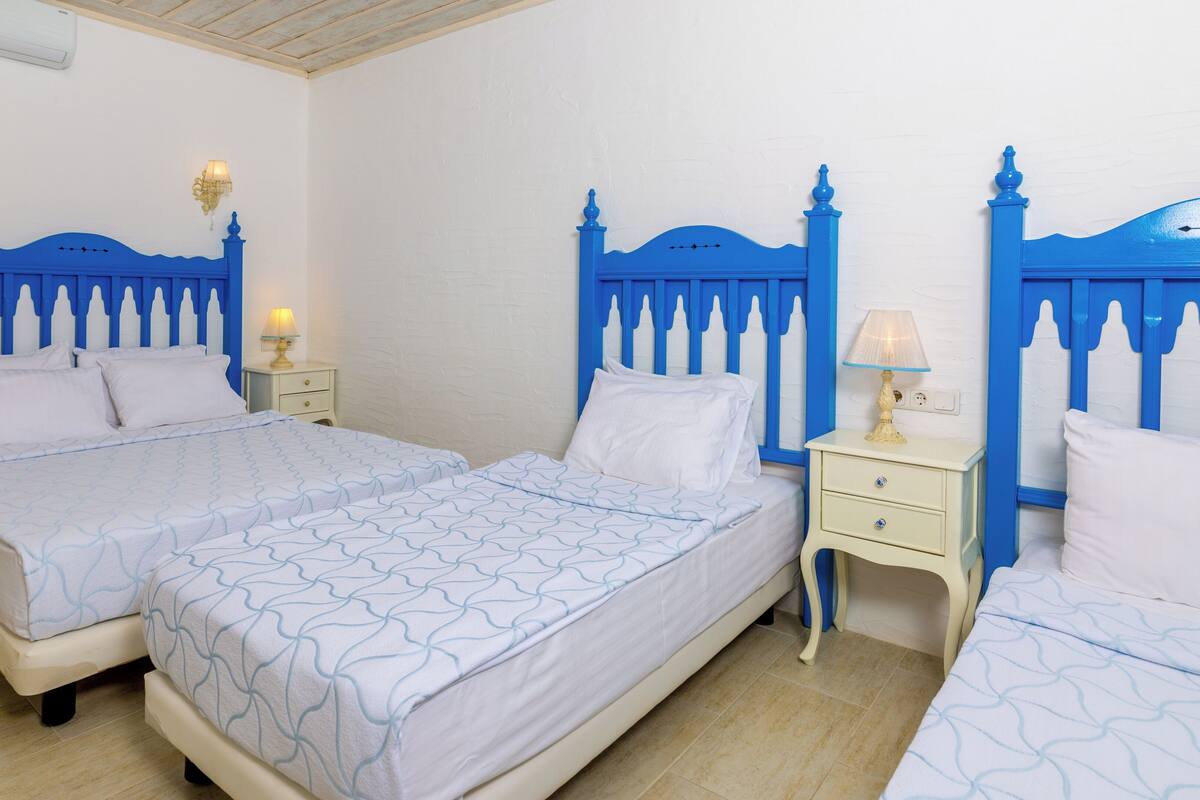 A double room with two beds, each with a blue headboard, white bedding, and bedside lamps.