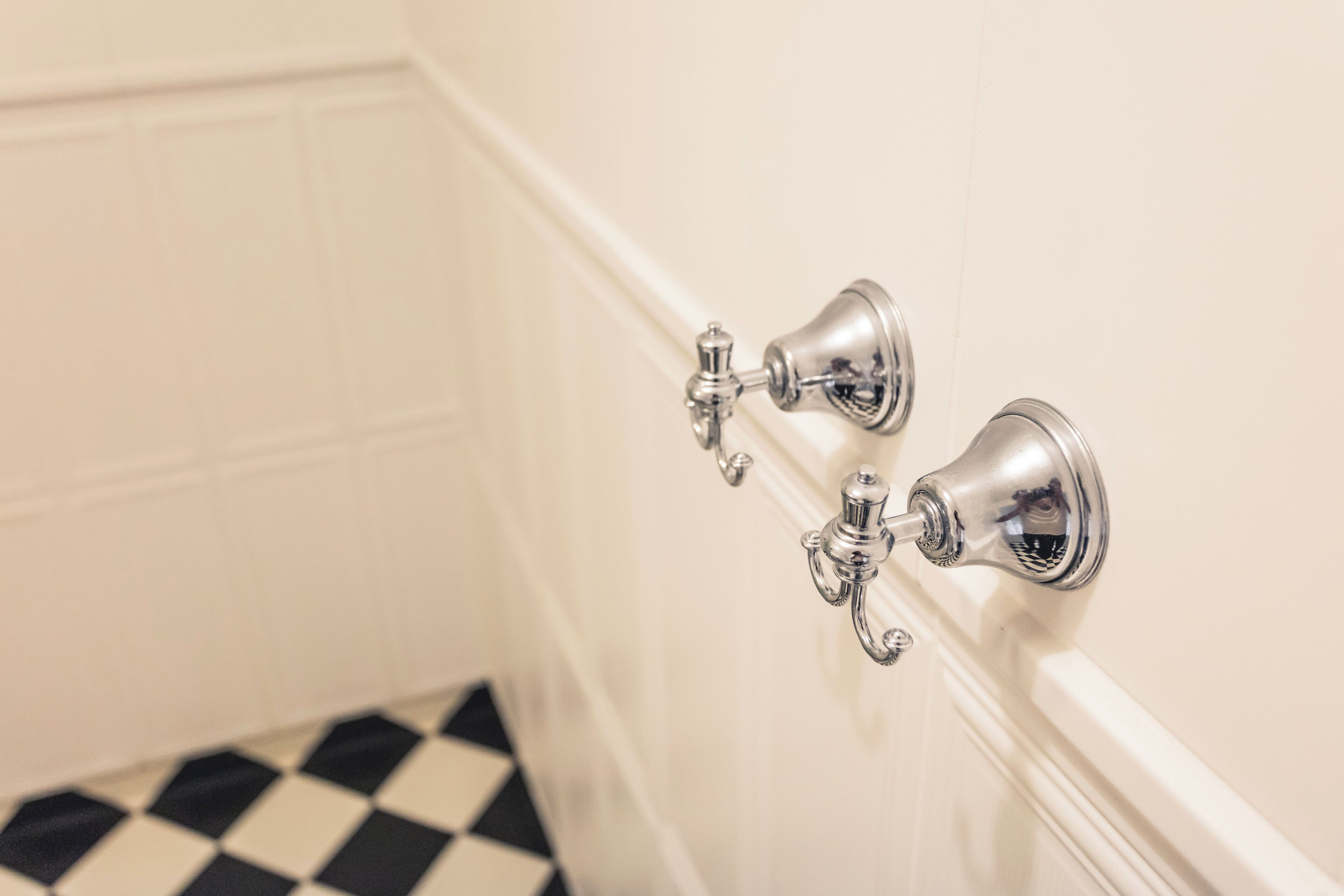 A bathroom with a white tiled floor and a white wall.