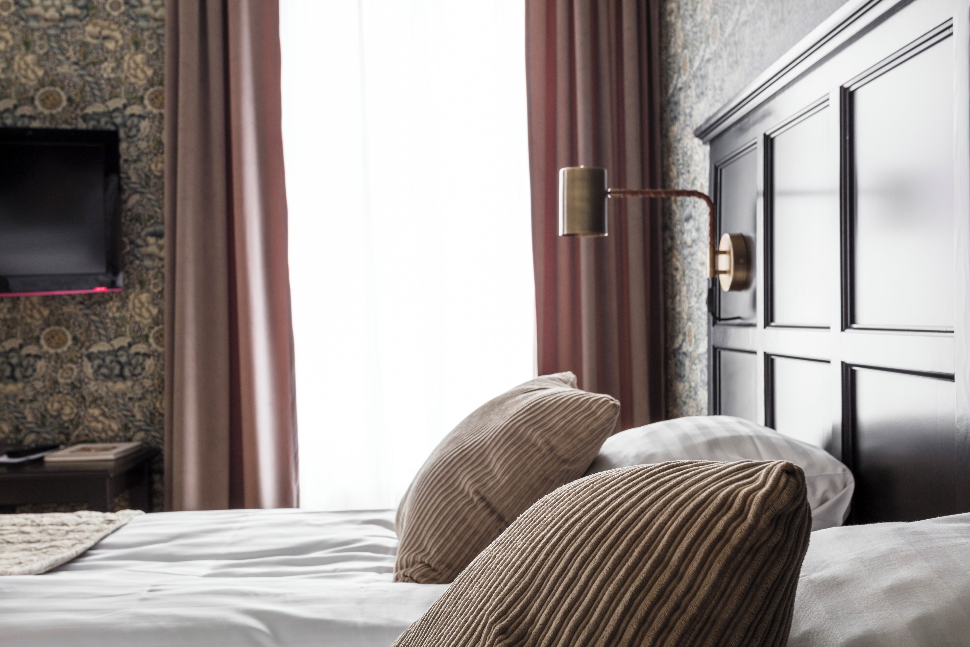 Ein Hotelzimmer mit Bett, Wand-Fernseher und Nachttisch.
