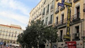 A street with buildings, a tree, and people walking. - Hostal Victoria I (Madrid)