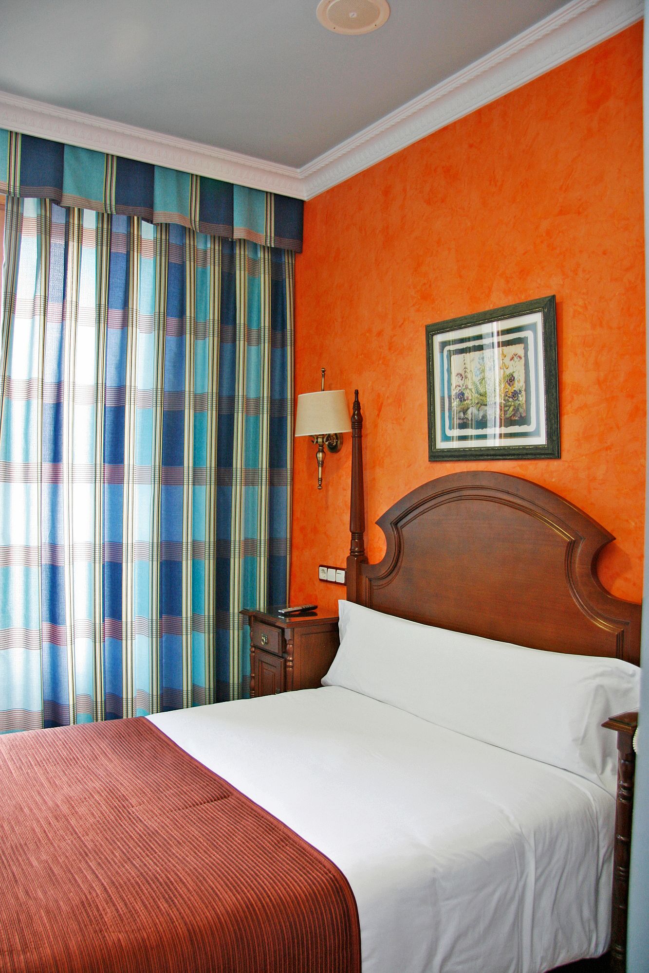Une chambre d’hôtel avec un grand lit, une table de chevet, une lampe et un tableau encadré au mur.