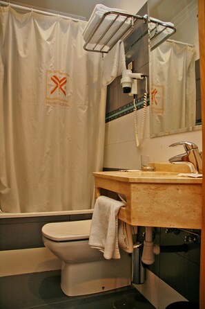 A bathroom with a toilet, a sink, a mirror, and a shower curtain. - Hostal Victoria II (Madrid)