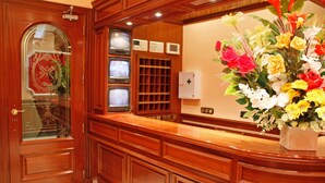 Een receptiegedeelte met een houten receptiebalie, een glazen deur met een decoratieve krans en een aan de muur bevestigde telefoon.