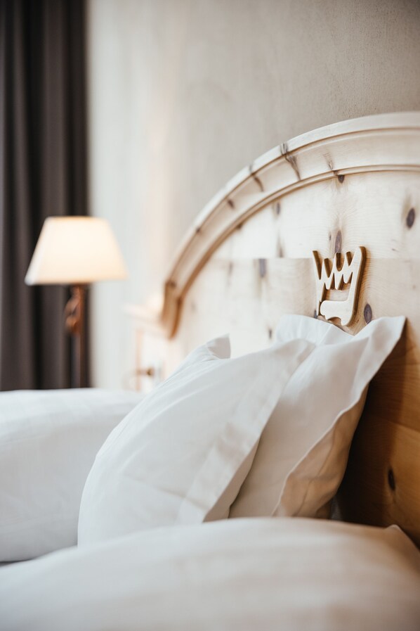 A neatly made bed with white linens and a wooden headboard with a crown design.