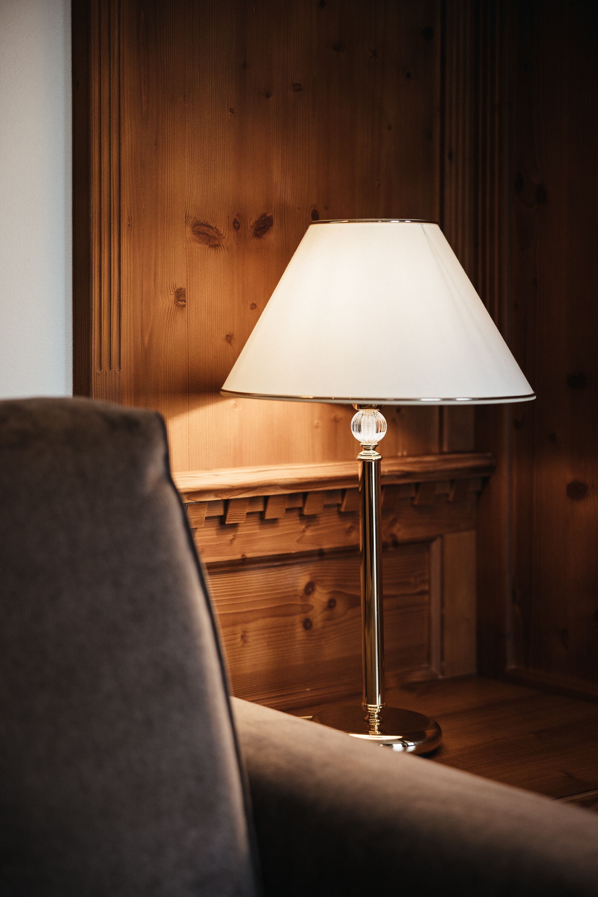 Una lámpara con pantalla blanca sobre una superficie de madera.