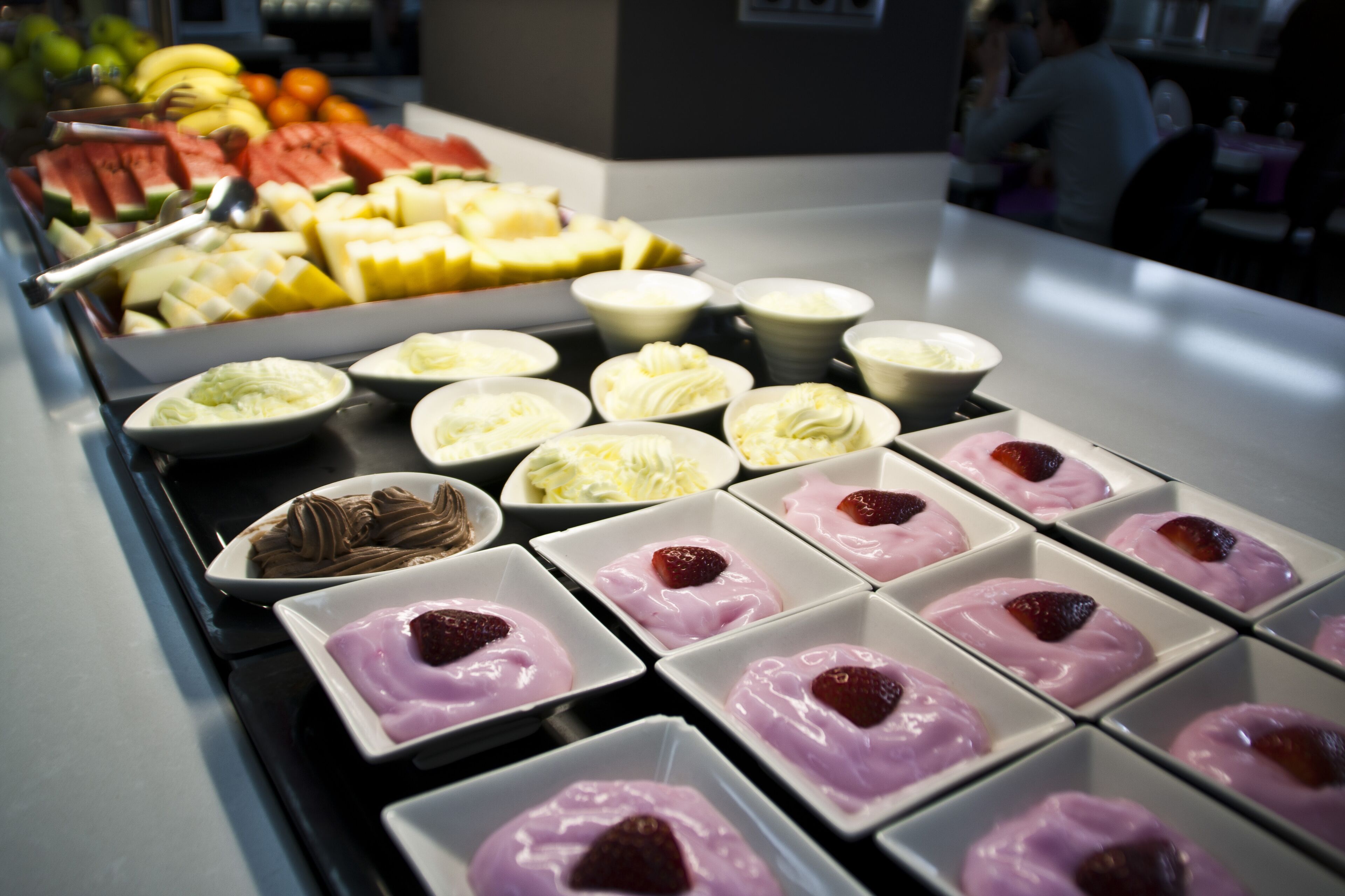 Un bufé con diversas opciones de comida, incluyendo frutas, postres y una selección de bebidas.