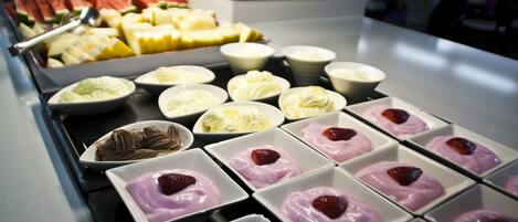 Un bufé con diversas opciones de comida, incluyendo frutas, postres y una selección de bebidas.