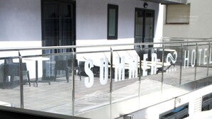 A white tufted sofa in a hotel lobby with a view of the outdoor seating area and a sign that reads "SUMMER HOTEL". - Summer Hotel (Calella)