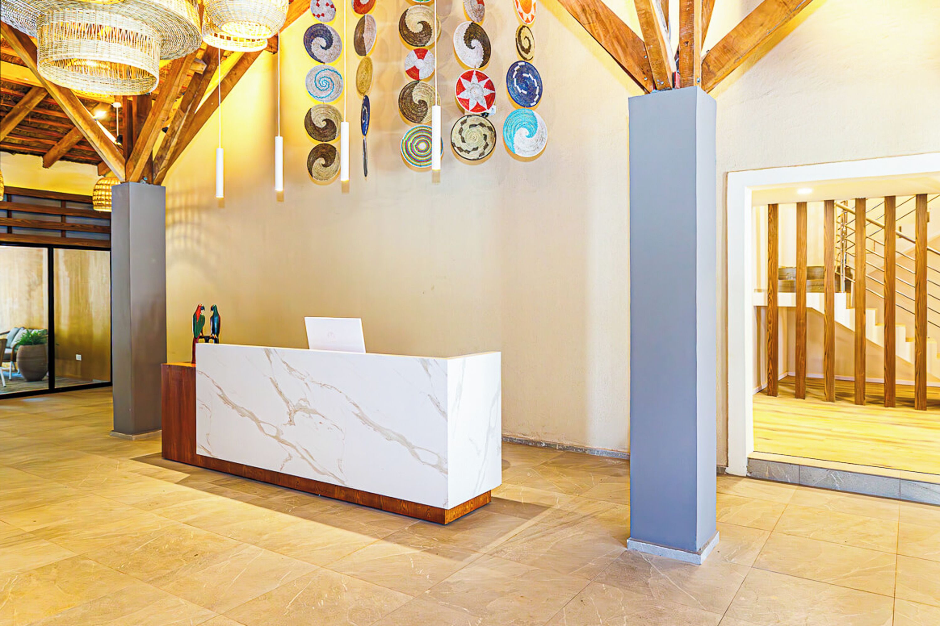 A reception area with a marble reception desk, a wall with circular wall art, and a staircase with wooden railings.