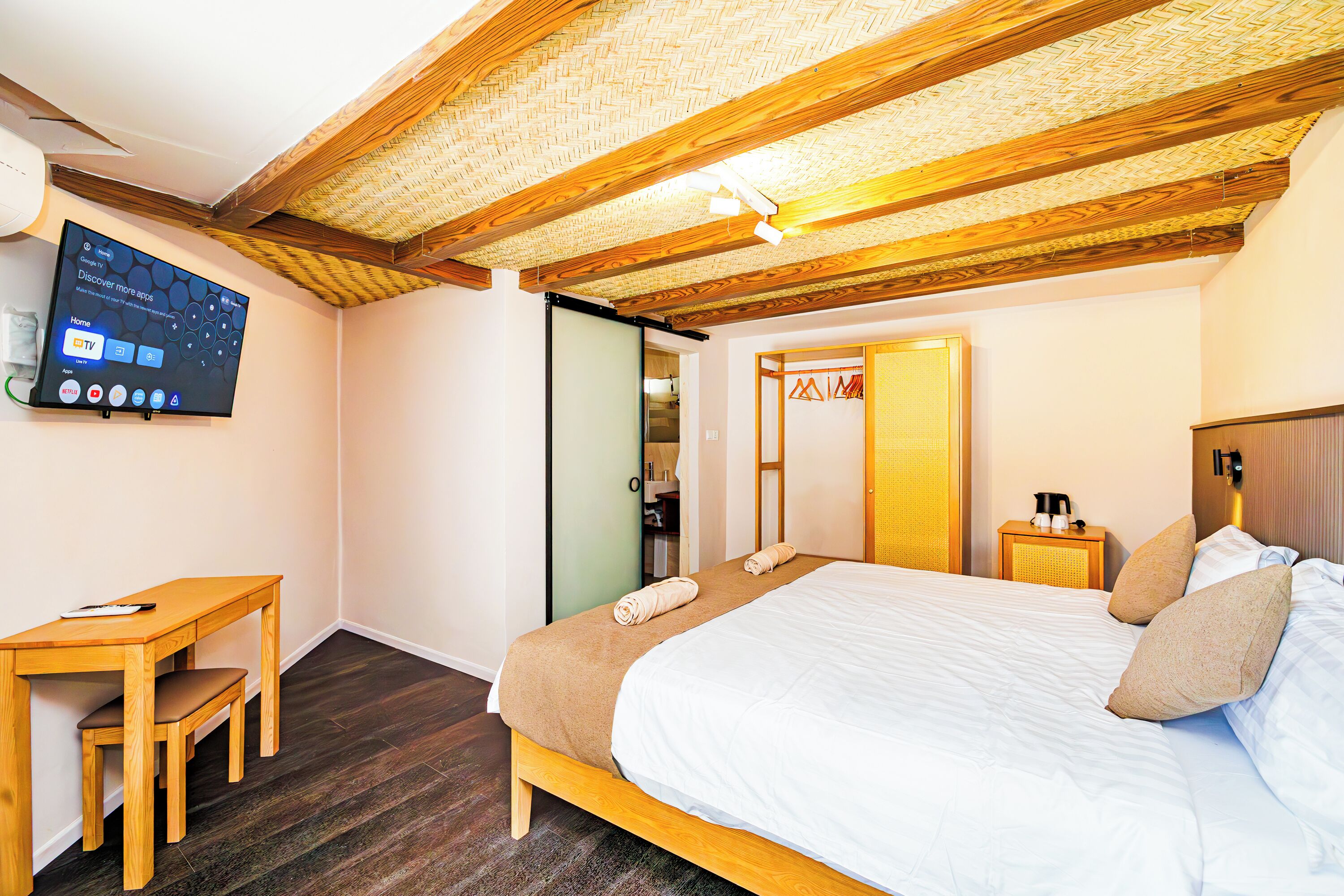 A bedroom with a bed, a desk, a chair, a TV, and a wardrobe.