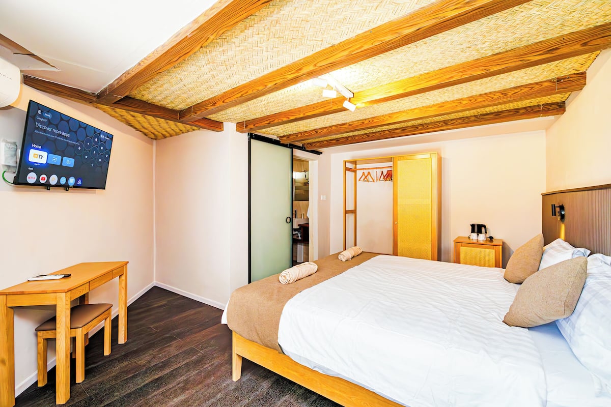 Une chambre à coucher avec un lit, un bureau, une chaise, une télévision et une armoire.