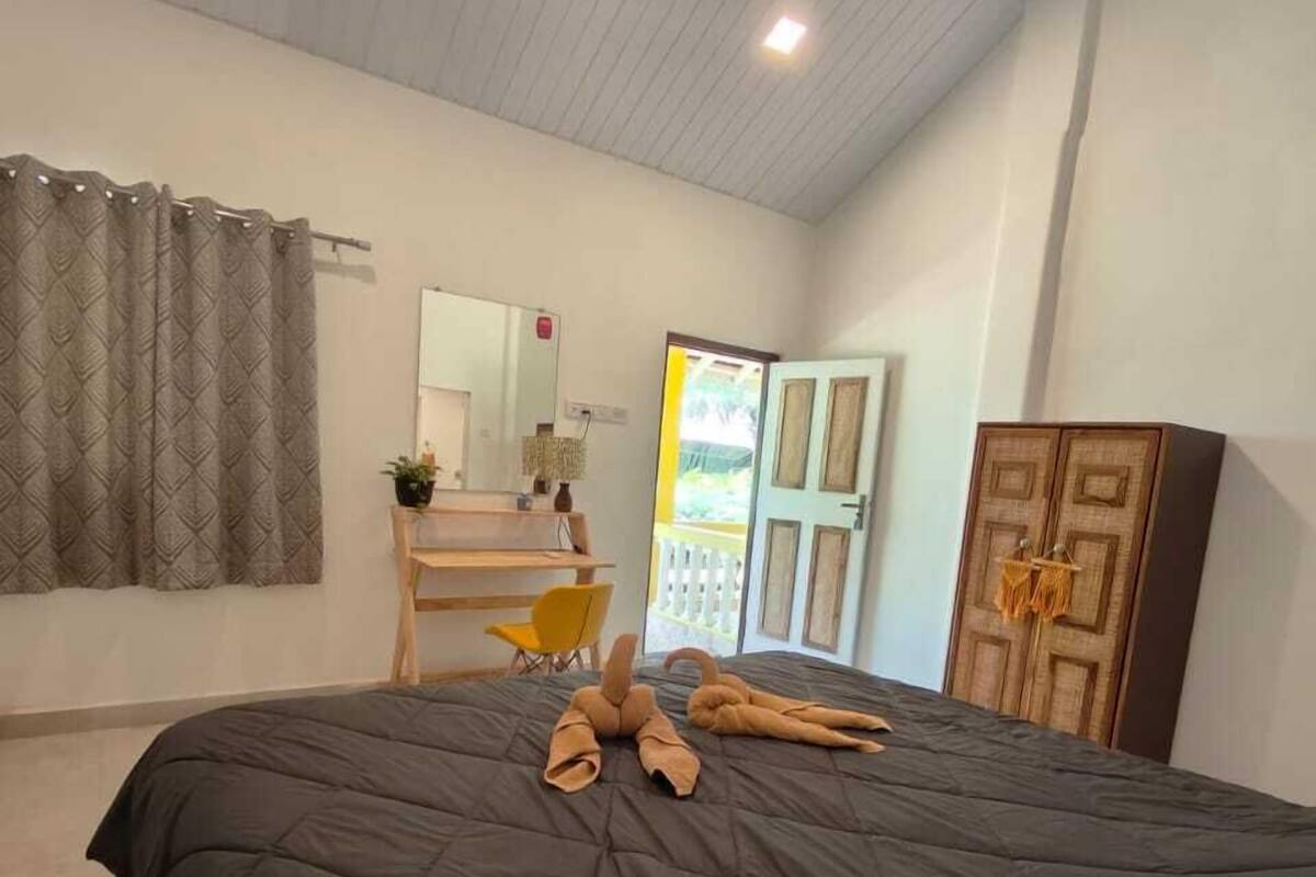 Un dormitorio con una cama grande, un armario de madera, un escritorio con silla y una ventana con cortinas.