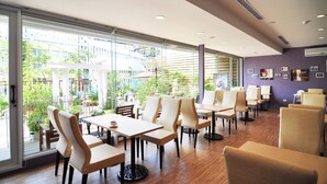 A modern indoor dining area with large windows, wooden flooring, and a mix of white and beige chairs. - Mirador Hotel Kaohsiung (Kaohsiung)