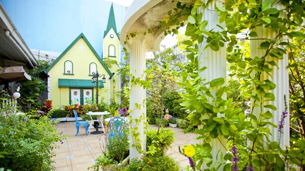 A courtyard with a yellow building, a white column, and various plants. - Mirador Hotel Kaohsiung (Kaohsiung)