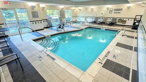 An indoor swimming pool with clear safety markings, lounge chairs, and a lifeguard station. - Fairfield Inn & Suites by Marriott Harrisburg West (New Cumberland)