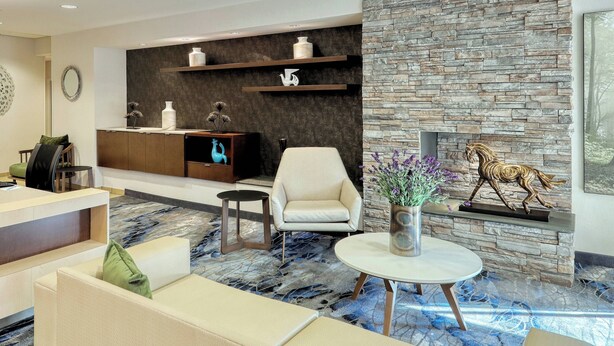 A modern living room with a stone wall, a fireplace, and a sofa. - Fairfield Inn & Suites by Marriott Harrisburg West (New Cumberland)