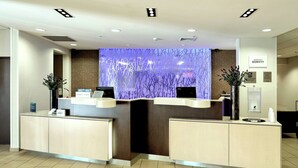 A hotel reception desk with two computer stations, a blue decorative wall, and a sign for the Bonvoy hotel. - Fairfield Inn & Suites by Marriott Harrisburg West (New Cumberland)