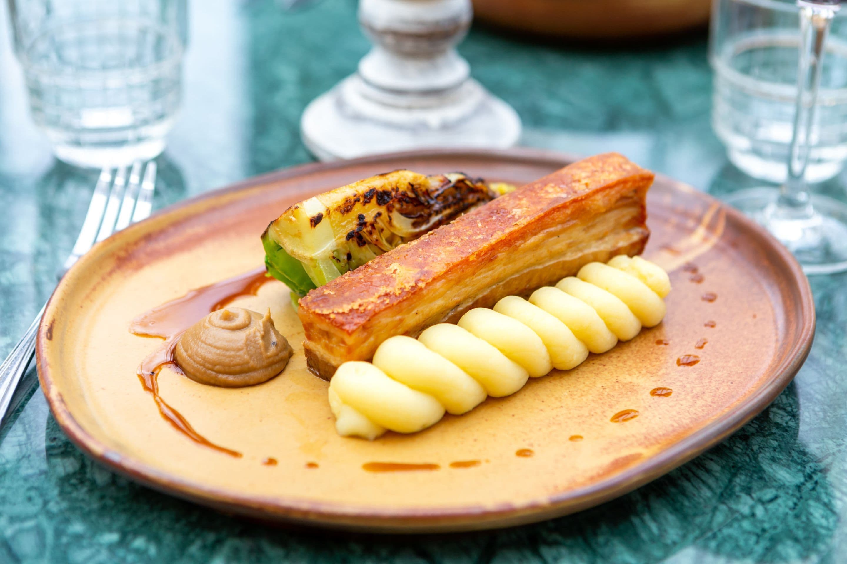 Un plato con un pastel, una cucharada de crema y una nuez pequeña sobre un plato de cerámica.
