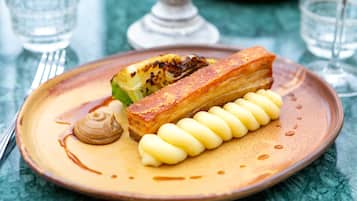 Un plato con un pastel, una cucharada de crema y una nuez pequeña sobre un plato de cerámica.