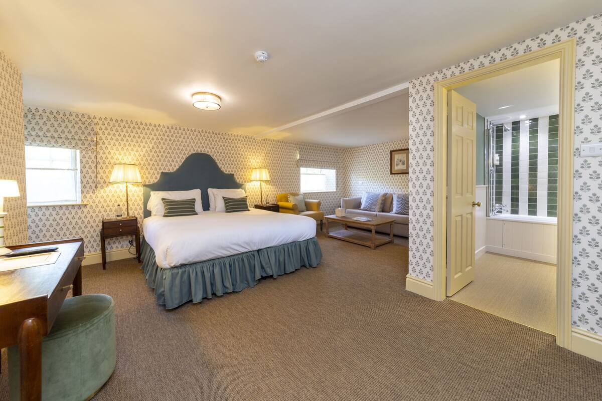 A bedroom with a bed, bedside tables, a desk, and a chair.