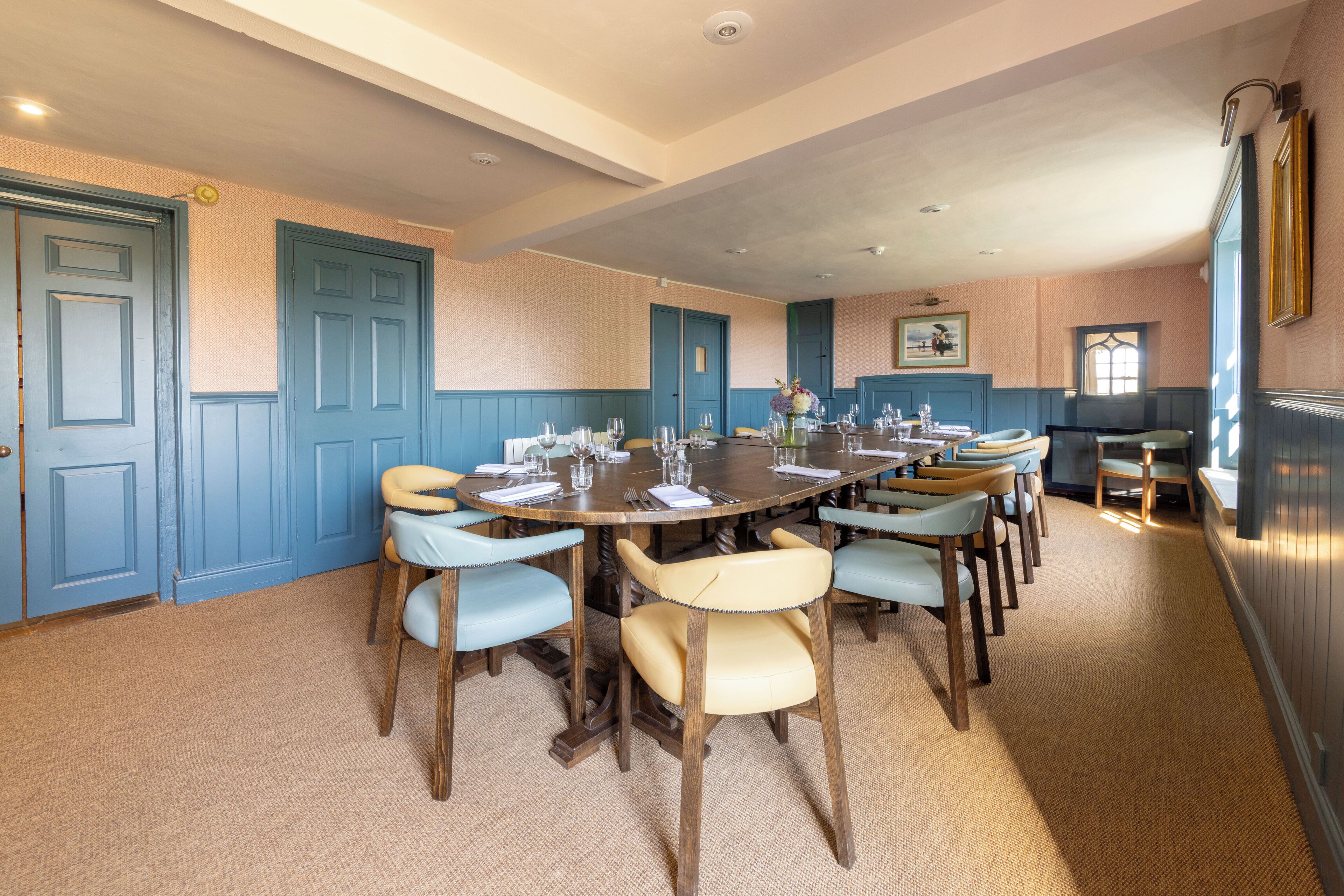 A dining room with a round table set for six, surrounded by six chairs with light blue upholstery.