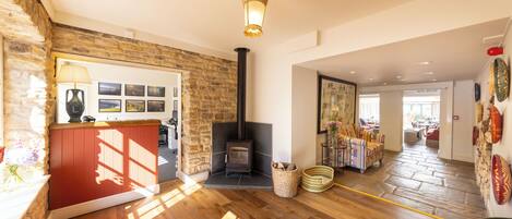 A spacious living room with a stone wall, a fireplace, wooden flooring, and a view into the dining area.