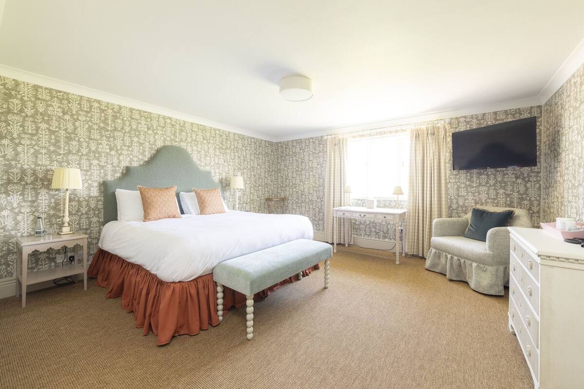 A bedroom with a bed, a desk, a chair, and a dresser.