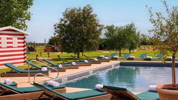 Relax by the pool surrounded by lush greenery and comfortable lounge chairs.