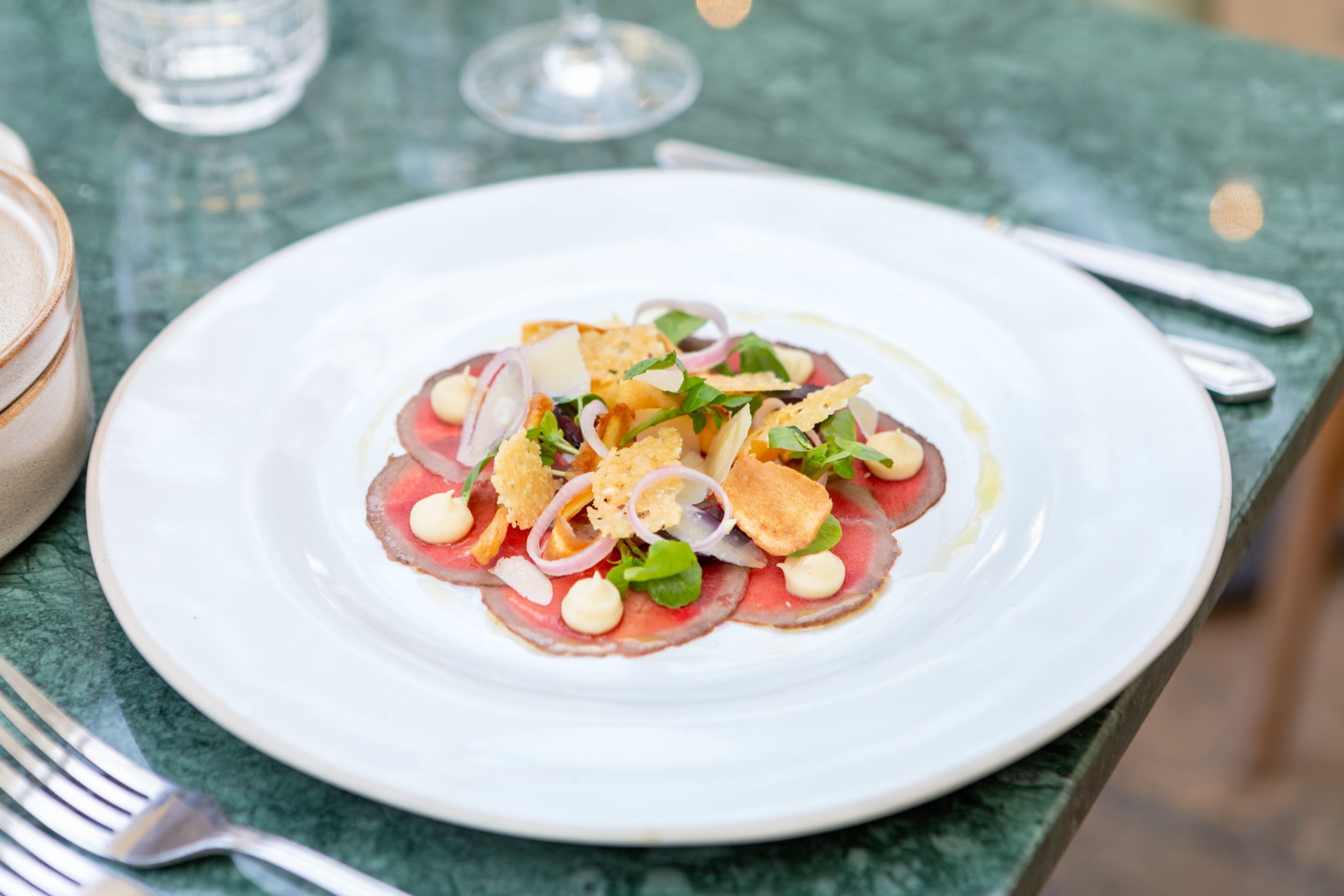 A white plate with a seafood dish on a green marble table.
