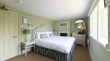 A bedroom with a bed, bedside table, dresser, and a large window.
