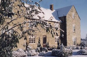 A stone building with a symmetrical facade, large windows, and a snow-covered roof. - The Barnsdale, Rutland (Oakham)