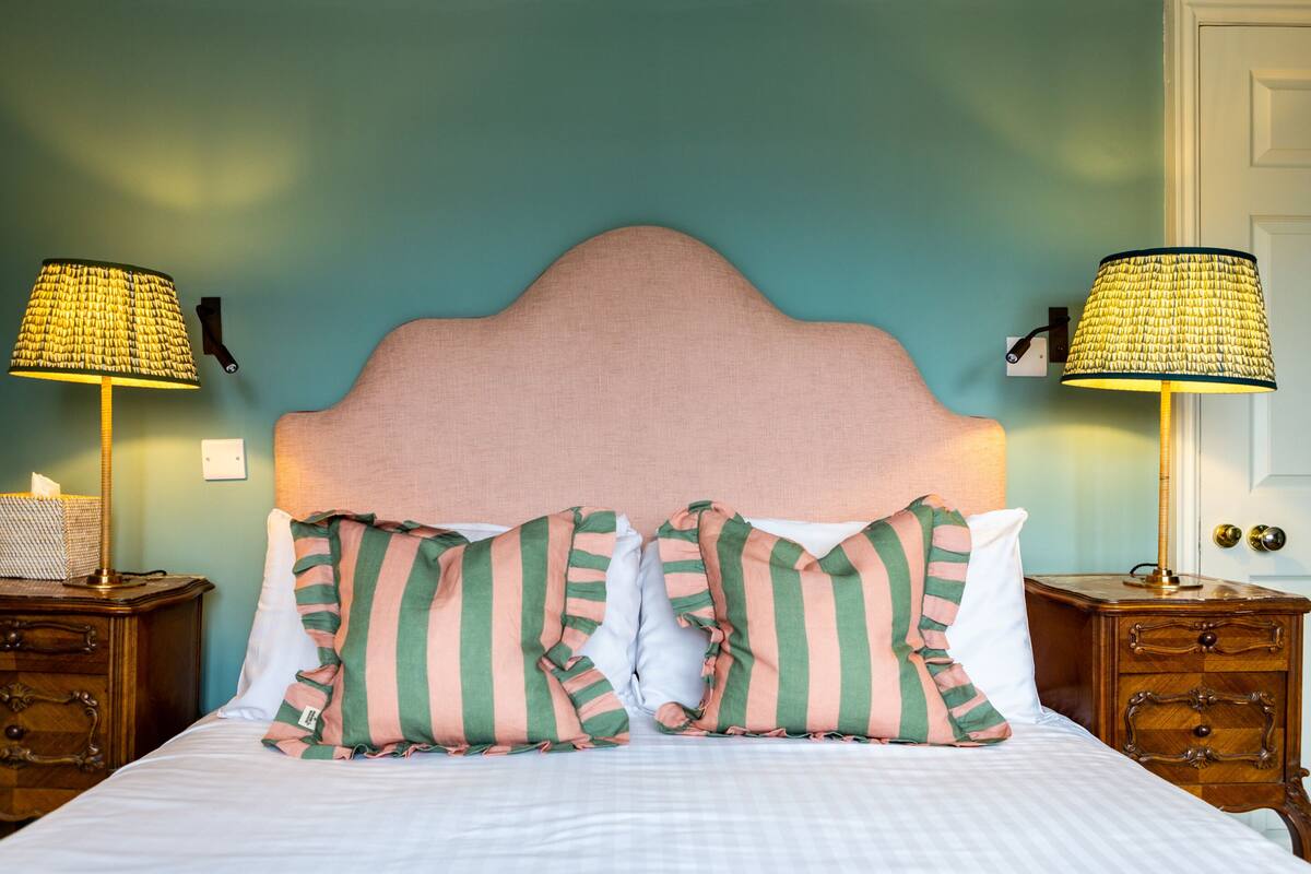 A neatly made bed with striped pillows, two bedside tables with lamps, and a wall with a textured pattern.