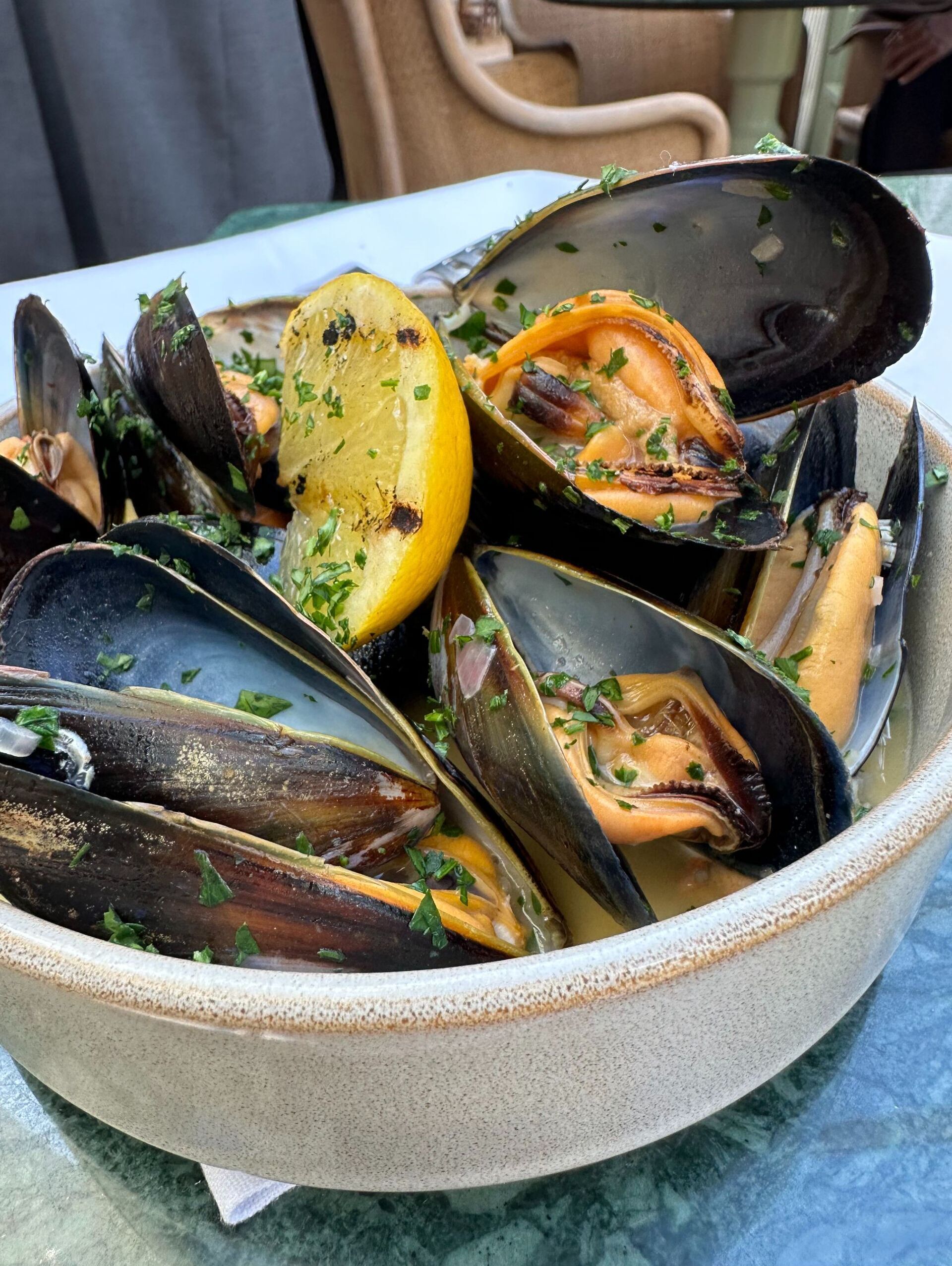 Una ciotola di cozze con fette di limone e guarnizione di prezzemolo.