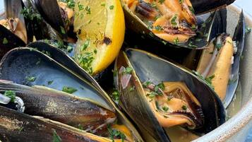 Una ciotola di cozze con fette di limone e guarnizione di prezzemolo.